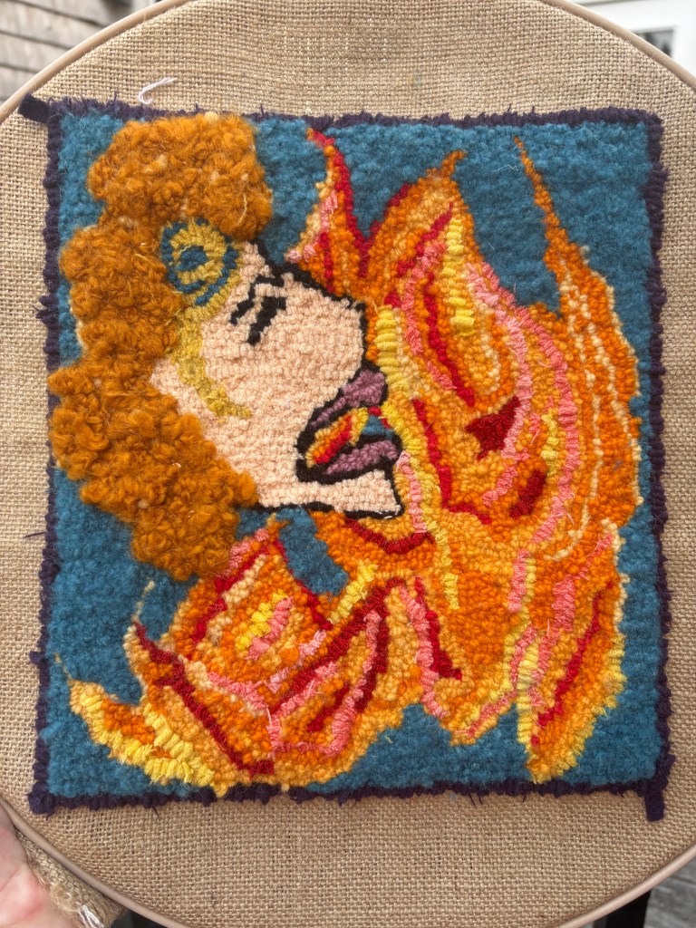 Hooked rug made of wool strips and yarn. Features a side profile of a woman yelling, her eyes closed. Her hair is raised, textured ginger yarn. Behind her image are orange, yellow and red flames made of wool strips and yarn.